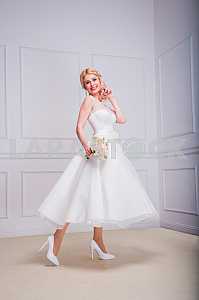 Blonde beautiful bride in short dress with wedding bouquet