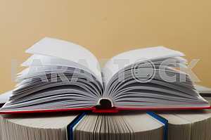Открытая книга, стопка книг в твердом переплете на деревянном столе. Обратно в школу. Копирование пространства