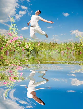 Happy young man - jumping. Reflected in Water