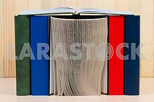 Открытая книга, стопка книг в твердом переплете на деревянном столе. Обратно в школу. Копирование пространства