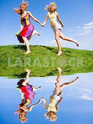 Two happy young women are runing in a field