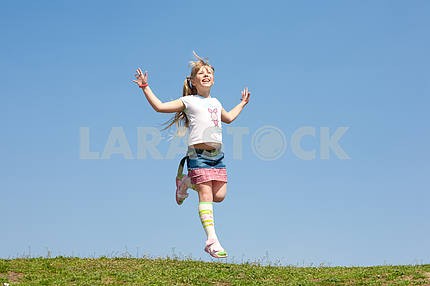 Маленькая девочка прыгает против красивых неба