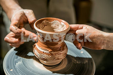 The potter on the potter's wheel teaches the child to make a pitcher from clay