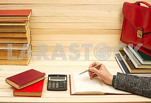 On a wooden table books, documents, calculator, red briefcase.