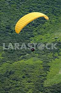 Paraglider flying over mountains on a summer day