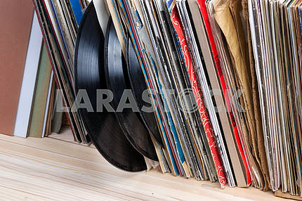 Retro styled image of a collection of old vinyl record lp's with sleeves on a wooden background. Copy space