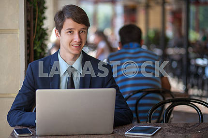 Один расслабленной молодой красивый профессиональный бизнесмен, работающий со своим ноутбуком , телефон и планшет в шумном кафе . говорить с телефоном .