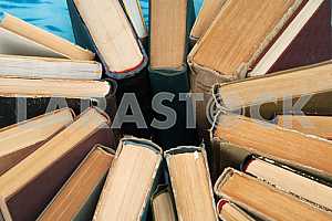 Old and used hardback books or text books on wooden table. Books and reading are essential for self improvement, gaining knowledge and success in our careers, business and personal lives. Copy space