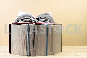 Открытая книга, стопка книг в твердом переплете на деревянном столе. Обратно в школу. Копирование пространства