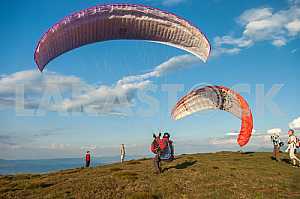 Paraglider flying over mountains on a summer day