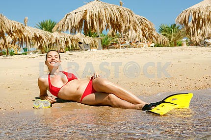 girl in a red bikini with a mask and flippers on the beach