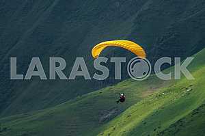 Paraglider flying over mountains on a summer day