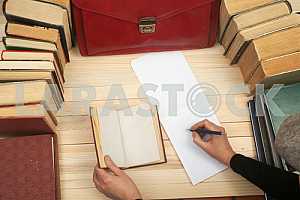 On a wooden table books, documents, calculator, red briefcase.