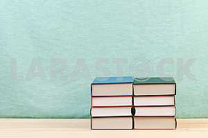 Открытая книга, стопка книг в твердом переплете на деревянном столе. Обратно в школу. Копирование пространства