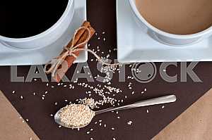 Black coffee and coffee with milk in white cups. Cinnamon and sesame.