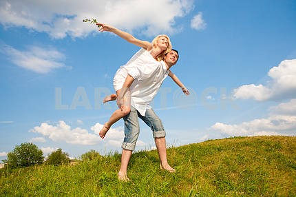Happy young couple  jumping in sky above a green meadow