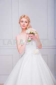 Blonde beautiful bride in short dress with wedding bouquet