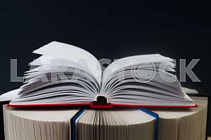 Открытая книга, стопка книг в твердом переплете на деревянном столе. Обратно в школу. Копирование пространства