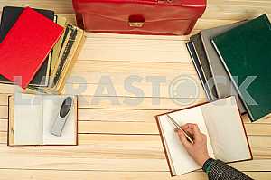 On a wooden table books, documents, calculator, red briefcase.