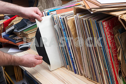 Retro styled image of a collection of old vinyl record lp's with sleeves on a wooden background. Copy space