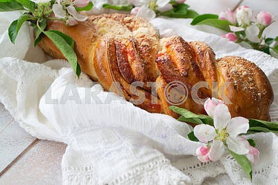 Sweet wicker bun with strowberry on wooden table with lacy knitted napkin and spring flowers.