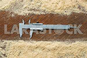 Different construction tools on a wooden background - screwdriver, caliper.