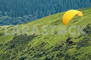 Paraglider flying over mountains on a summer day