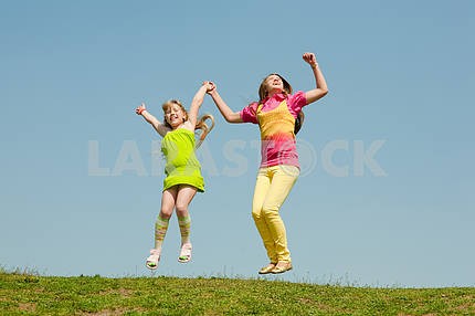 Две девушки прыжки на зеленый луг