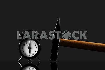 wake up with a hammer on a black background. Black old style alarm clock isolated