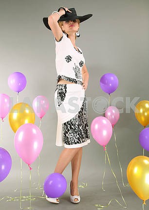 Beautiful young girl in light dress a hat on background balloons