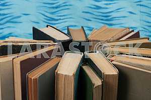 Old and used hardback books or text books on wooden table. Books and reading are essential for self improvement, gaining knowledge and success in our careers, business and personal lives. Copy space