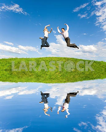 Happy Young Couple - team is jumping in the sky above a green me