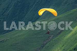 Paraglider flying over mountains on a summer day