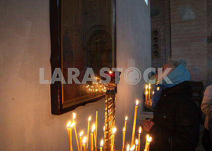 A woman of old age prays for the icon of Pokrov
