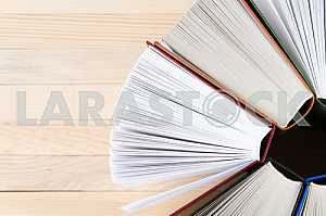 Открытая книга, стопка книг в твердом переплете на деревянном столе. Обратно в школу. Копирование пространства