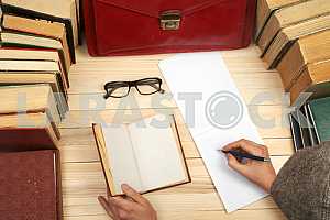 On a wooden table books, documents, calculator, red briefcase.