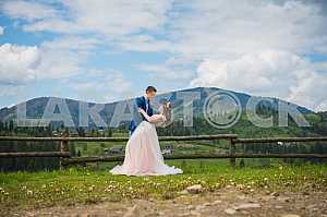 Couple in love looking at each other, dancing, mountains on the background, blue sky with the coulds, Carpatian mountains. shot from below, Loving couple marriage
