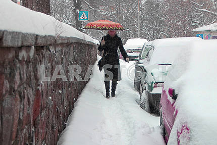 A woman is walking along a snow-covered street in Kiev