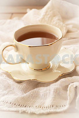 Tea in a white pot of a cup on a white vintage napkin background, vertical image