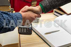 On a wooden table books, documents, calculator, red briefcase.