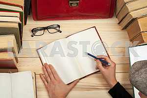 On a wooden table books, documents, calculator, red briefcase.