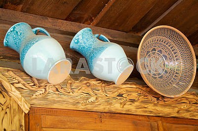 Ceramic glazed blue jugs and traditional clay bowl on wooden background.