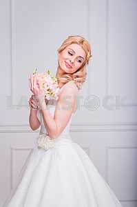 Blonde beautiful bride in short dress with wedding bouquet