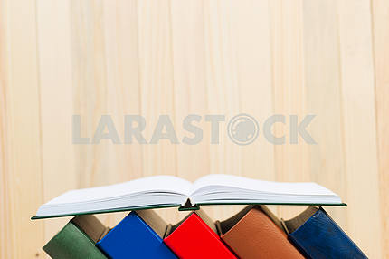 Open book, stack of hardback books on wooden table. Back to school. Copy space