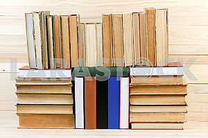 Открытая книга, стопка книг в твердом переплете на деревянном столе. Обратно в школу. Копирование пространства