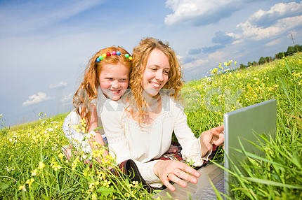 Mom and Daughter with laptop resting on meadow