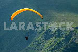 Paraglider flying over mountains on a summer day