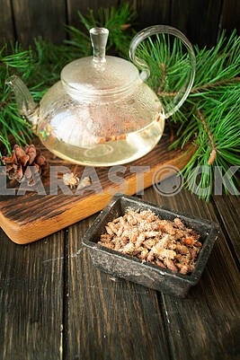 Tea pot of herbal tea with pine buds on wooden background