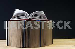 Открытая книга, стопка книг в твердом переплете на деревянном столе. Обратно в школу. Копирование пространства