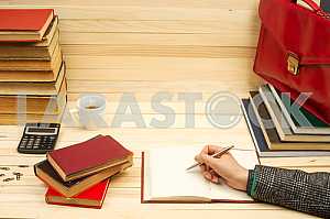 On a wooden table books, documents, calculator, red briefcase.